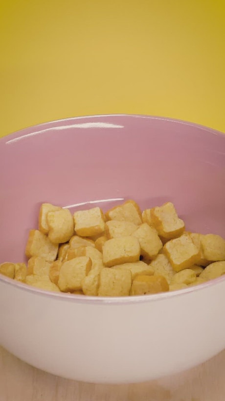 Pouring milk into a pink bowl with cereal.