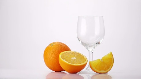 将橙汁倒入白底玻璃杯中