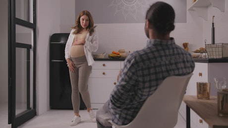 Pregnant woman and her husband hanging out in home.