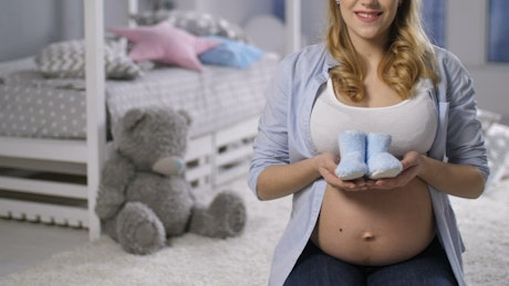 Pregnant woman holding baby shoes