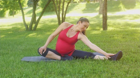 Pregnant woman stretching in the park