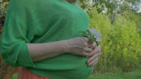 Pregnant woman walking through woodland.