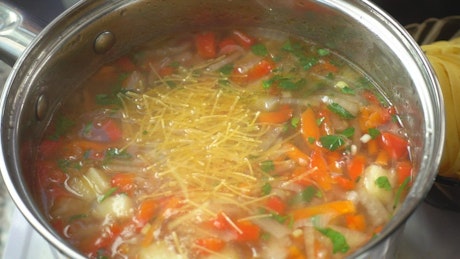Preparing vegetable and pasta soup.