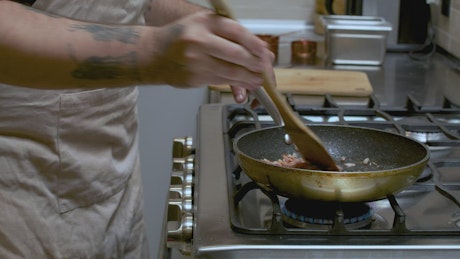 Professional cook frying bacon in a frying pan