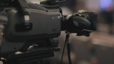 Professional video camera on a tripod recording a talk