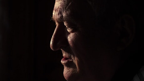 Profile face of an sad old man in the dark