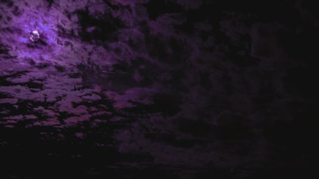 Purple glow moon moves through clouds.