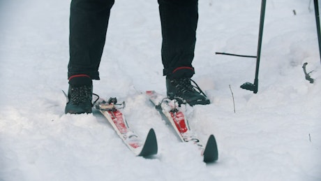 Putting feet up on a pair of skis in the snow.