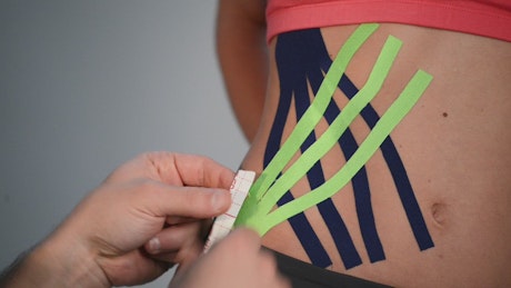 Putting kinesio tape on an athlete's hip