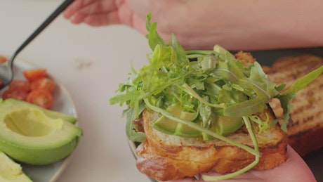 Putting salad on a slice of bread.