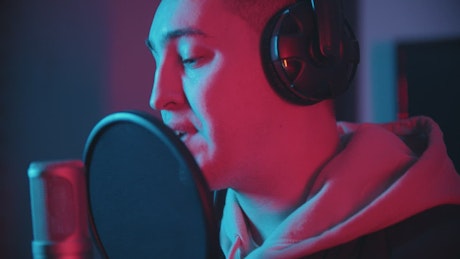 Rapper recording with a microphone in a recording studio.