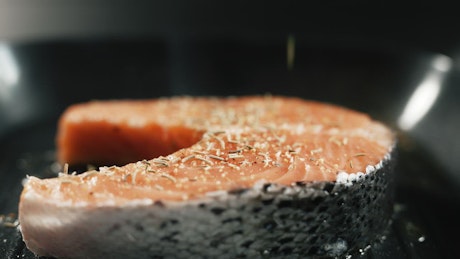Raw salmon over a heated grill.