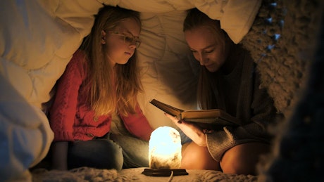 Reading a book in a blanket fort