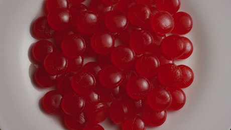 Red candies slowly spinning on a plate.