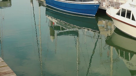 Reflections of boats in a harbor.