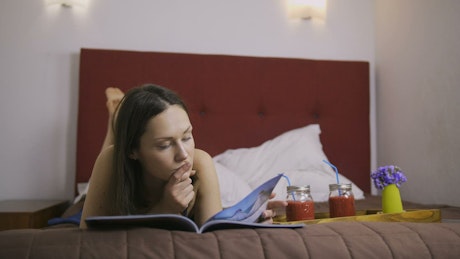 Relaxed woman reading a book lying on her bed.