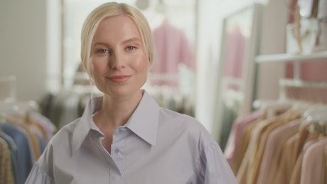 Retail worker smiling at the camera at a clothes shop.