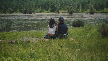 Romantic couple sitting on the shore of a lake.