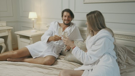 Romantic couple toasting with champagne in a hotel room.