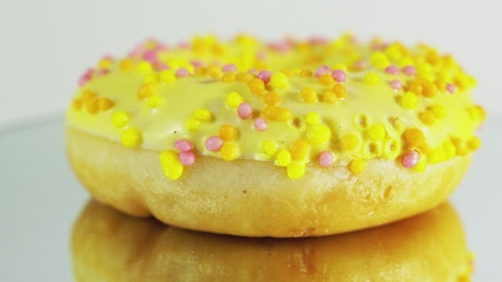 Rotating donut with yellow icing and sprinkles.