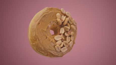 Rotating peanut butter donut on a pink background