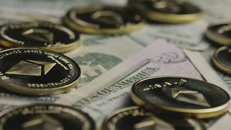 Rotating shot of Ethereum kinds over dollar bills