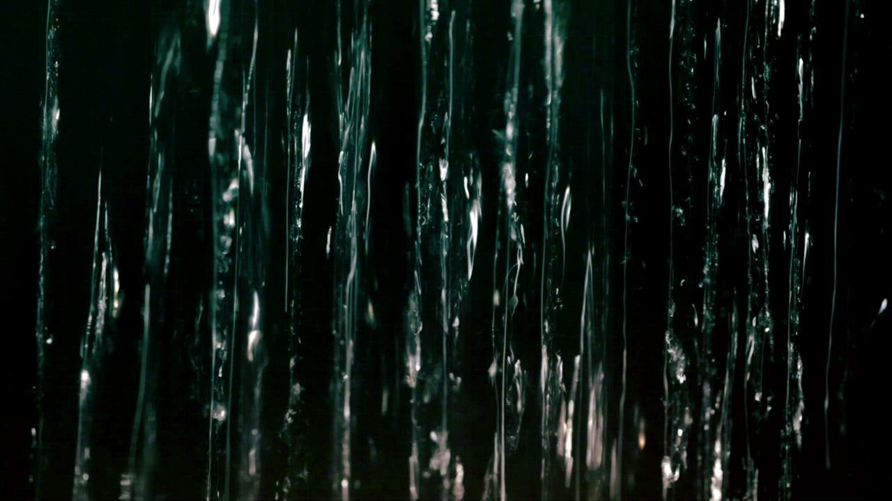 Running water falling against a dark screen - Free Stock Video