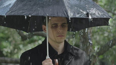 Sad man at a funeral raining with umbrella.