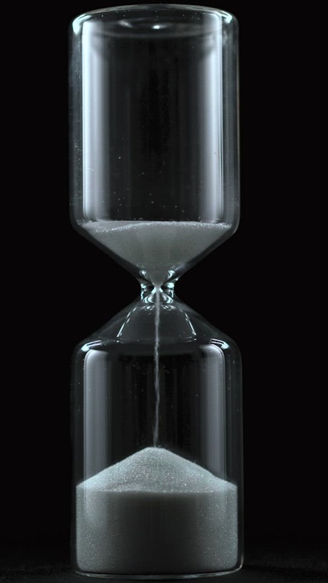 Sand falling from an hourglass on a black background.