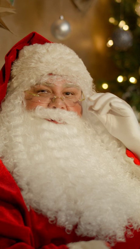Santa Claus in his classic red attire gently fixes his glasses and starts laughing.