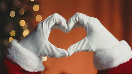 Santa making a heart sign with his hands.