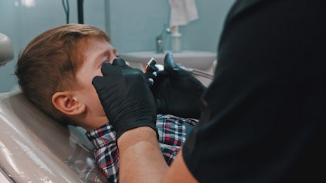 Scared little boy getting his teeth done with the dentist