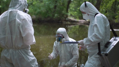 Scientist in biohazard suits collecting water.