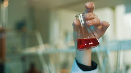 Scientist shaking a conical flask in the laboratory.