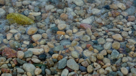 Sea waves reach the rocks on the beach, close up