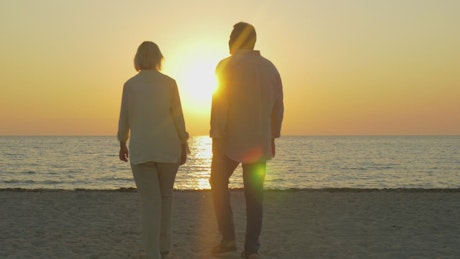 Senior couple walking at sunset.