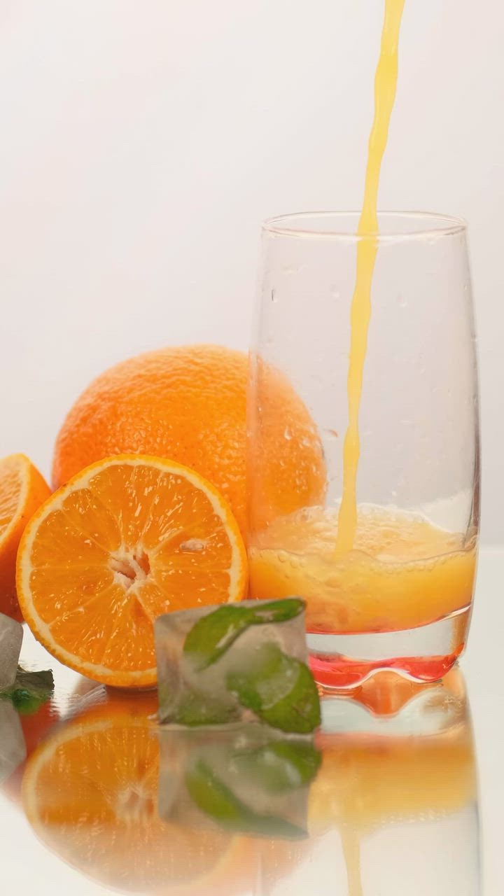 ⁣Serving juice  judibolaslot in a glass with some oranges on a white background