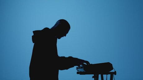 Shadow of a keyboardist playing on a blue background.