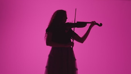 Shadow of a violinist playing on a pink background.