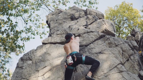 Shirtless man climbing a rock