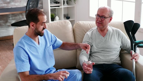 Sick man chats with nurse giving him medication