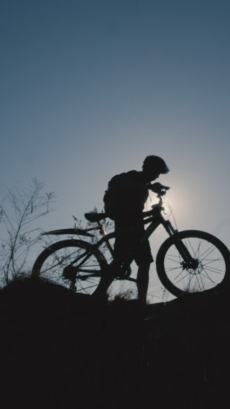 Silhouette in front of the sun of a cyclist outdoors.