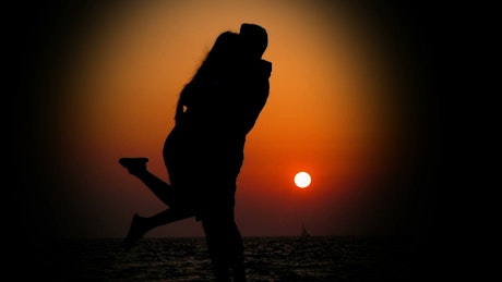 Silhouette of a couple hugging in the light of sunset.