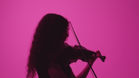 Silhouette of a female fiddler playing on a pink background.