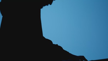 Silhouette of a keyboardist playing on a blue background.