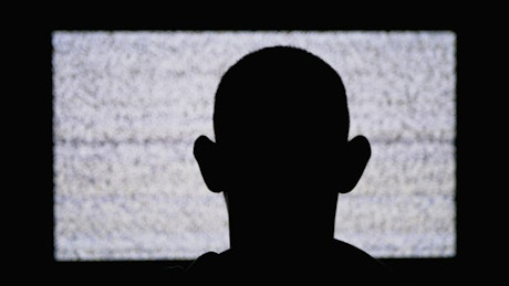 Silhouette of a man in front of a TV with static