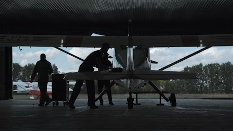 Silhouette of a man polishing a biplane