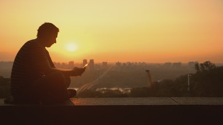 Silhouette of a man texting during the sunset.
