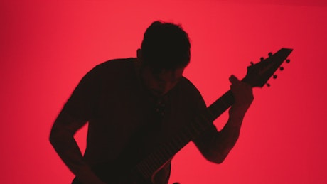 Silhouette of a rock musician playing on a red background.