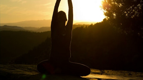 Silhouette of a woman doing yoga at sunset.